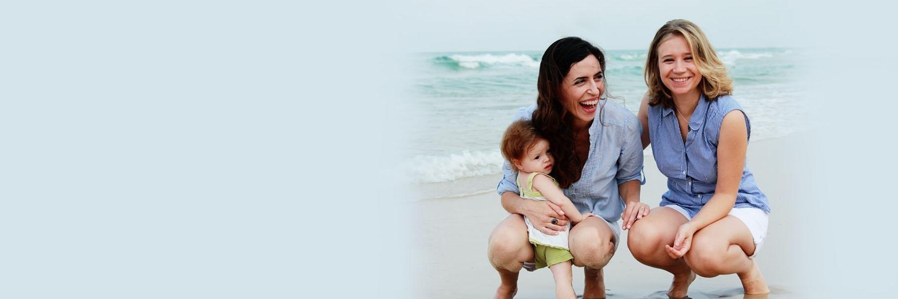two women and their child smiling on the beach